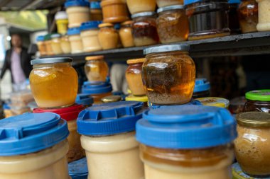 Mavi kapaklı bir kavanoz bal. Kavanozların boyutları ve renkleri farklı.