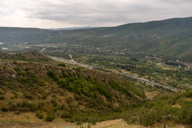 Ortasında otoyol olan bir dağ sırası. Otoyol araba ve kamyonlarla dolu.