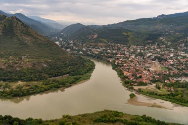 Arka planda yeşil bir vadi olan bir kasabanın içinden bir nehir akar. Kasaba dağlarla çevrili ve nehir çok güzel bir manzara.