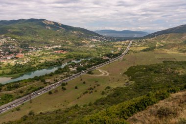 İçinden otoyol geçen bir dağ sırası. Otoyol araba ve kamyonlarla dolu. Sahne sakin ve sakin. Arka planda dağlar ve önde otoyol var.