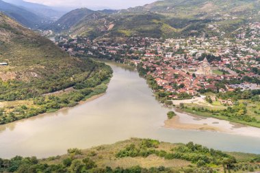 Uzakta bir şatosu olan bir kasabadan bir nehir akar. Su bulanık ve şehir ağaçlarla çevrili.