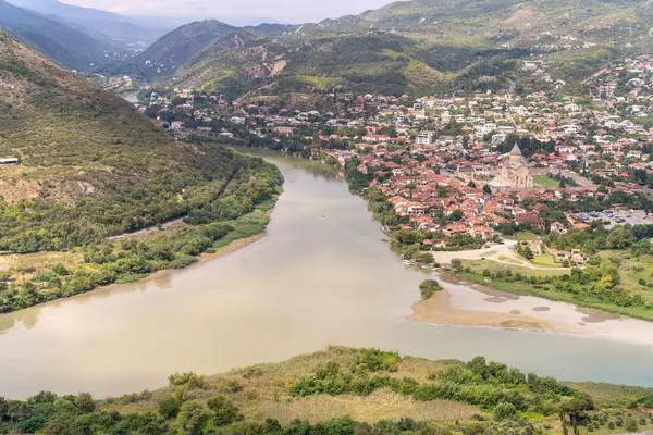 Uzakta bir şatosu olan bir kasabadan bir nehir akar. Su bulanık ve şehir ağaçlarla çevrili.