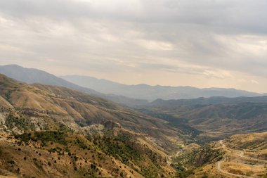 Dağlar yemyeşil ağaçlarla örtülmüş, gök de bulutlarla örtülmüştür. Sahne sakin ve sakin, dağlar manzara için güzel bir zemin sağlıyor.