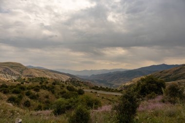 Arka planda dağlar olan bulutlu bir gökyüzü. Gökyüzü bulutlu ve dağlar uzak.