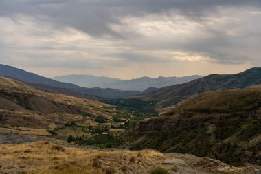 Birkaç ağacın etrafa saçıldığı uçsuz bucaksız, boş bir manzara. Gökyüzü bulutlu, ortama kasvetli ve kasvetli bir atmosfer veriyor. Manzaranın boşluğu bir yalnızlık hissi veriyor.