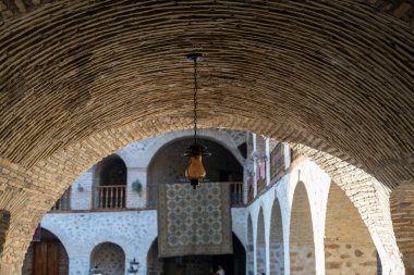 Kemerli pencereli bir binanın tavanından sarkan bir ışık. Işık odanın ortasındaki tavandan sarkıyor.