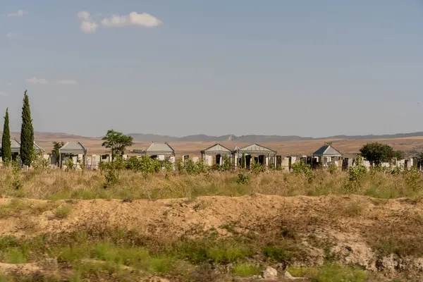 İçinde bir sürü küçük ev ve mezarlık olan bir tarla. Evler metalden yapılmış ve mezarlık mezarlıklarla dolu.
