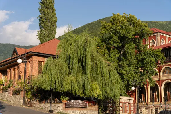 Önünde büyük bir ağaç olan bir bina. Bina kırmızı ve üzerinde bir işaret var.