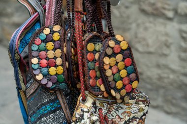 Üzerinde boncuklar asılı renkli çantalar koleksiyonu. Cüzdanlar duvarda ya da askıda asılı.