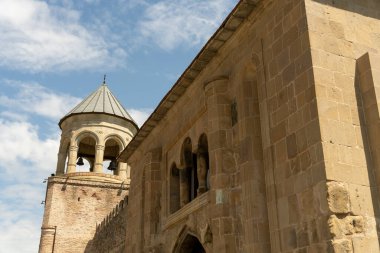 Çan kulesi ve kemerli pencereleri olan büyük taştan bir bina. Bina eski ve bir tarih anlayışı var.