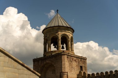 Üstünde çan olan bir çan kulesi. Gökyüzü bulutlu.