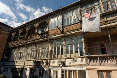 Bir sürü penceresi olan ve çatıda kırmızı bayrak sallanan bir bina. Bina eski ve çatıdan bir sürü kablo sarkıyor.