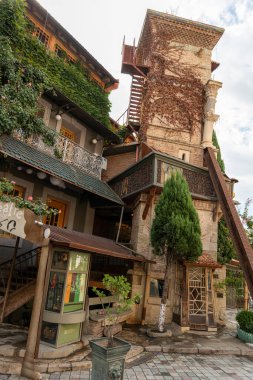 Önünde yeşil bir ağaç ve yeşil çatılı bir bina. Binanın üzerinde 