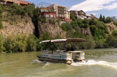 Nehirde tepesinde bir gölgelik olan bir tekne var. Kubbe açık ve tekne hareket ediyor.