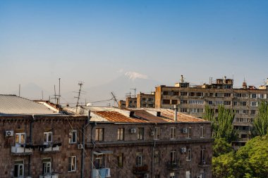 Arkasında dağ olan bir şehir silueti. Binalar eski ve gökyüzü temiz.