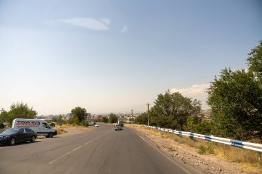 Üzerinde kamyonet ve minibüs olan bir yol. Gökyüzü açık ve güneş parlıyor.