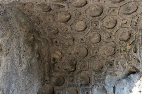 Daireler ve karelerden oluşan bir duvar. Duvar taştan yapılmış ve o yaşlı. Duvardaki desen çok karmaşık ve detaylı.