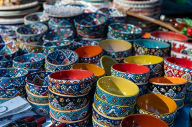 Bir masa dolusu renkli kase ve tabak. Kâseler bir şekilde üst üste istiflenmiş vaziyette dizilmiştir. Kâselerin renkleri ışıl ışıl ve neşe saçıyor.