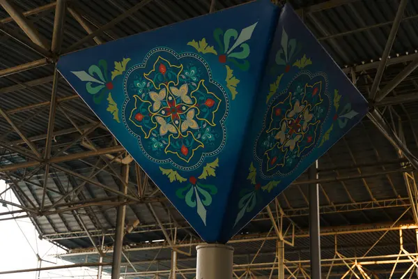 Metal bir direkte mavi ve yeşil bir tasarım. Tasarımı karmaşık ve renklidir. Manzara canlı ve canlı.