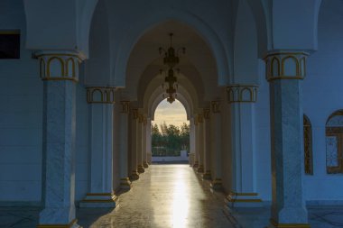 Kemerli tavanları ve altın aksanlı uzun, dar bir koridor. Işık kemerlerin arasından parlıyor, sıcak ve davetkar bir atmosfer yaratıyor.