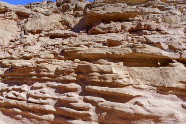 Bir sürü dokusu ve bir kaç deliği olan kayalık bir uçurum. Görüntü engebeli ve pürüzlü, kayalar yıpranmış ve yıpranmış görünüyor. Kayalardaki delikler derinlik duygusunu arttırıyor.