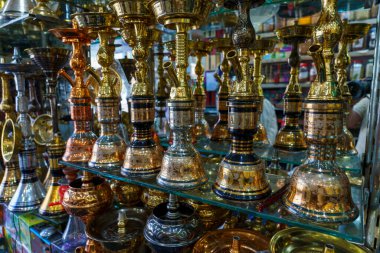 Altın ve gümüş renkli vazolar ve kâseler sergileniyor. Vazolar ve kaseler bir rafa dizilmiştir ve çeşitli boyutlardadır.