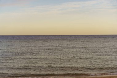 Okyanus sakin ve gökyüzü mavinin güzel bir tonu. Su koyu mavi bir renktir ve gökyüzü açık mavi bir renktir.