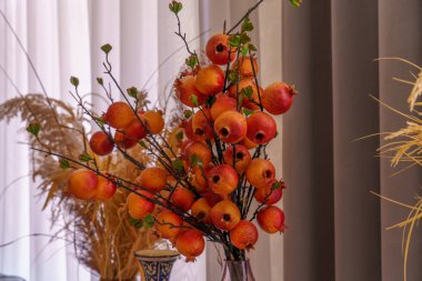 Bir vazoda elma ve nar gibi güzel bir meyve düzenlemesi sergilenmektedir. Narlar aranjmanın odak noktasıdır.