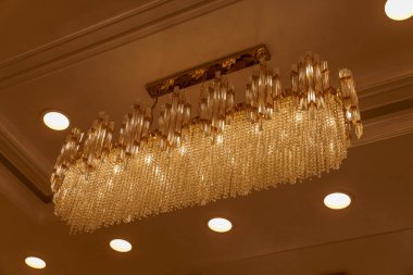 Tavandan bir sürü kristal parçalı büyük bir avize sarkıyor. Avize camdan yapılmıştır ve altın bir çerçeveye sahiptir. Kristal parçalar güzel bir şekilde düzenlenir.