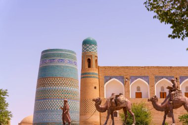 Mavi kubbesi ve mavi beyaz çizgili kulesi olan yüksek bir bina. Binada iki deve var.