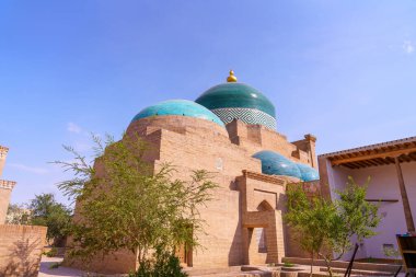 Tepesinde mavi kubbe olan bir bina. Bina tuğladan yapılmıştır. Binanın etrafında ağaçlar var.