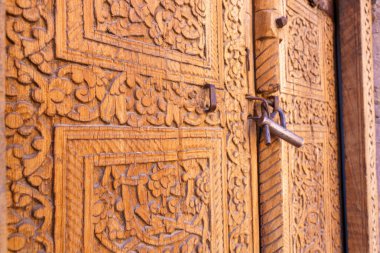 Üzerinde kilit olan ahşap bir kapı. Kilit gümüş ve anahtar deliği var. Kapıda çiçek deseni var.