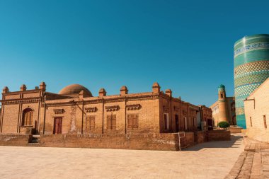 Mavi kubbeli bir bina mavi kubbeli başka bir binanın önünde duruyor. Mavi binanın tepesinde mavi bir kubbe var ve iki bina yan yana. Binalar tuğladan yapılmış.