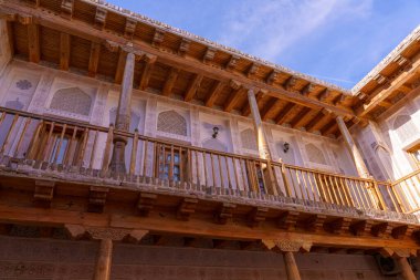 Tahta korkuluklu ve beyaz duvarlı bir balkon. Balkon binanın yan tarafında.