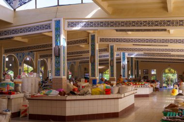 Bir sürü masası ve bir sürü insan olan büyük bir açık pazar. Satılık pek çok çeşit yiyecek ve eşya vardır.