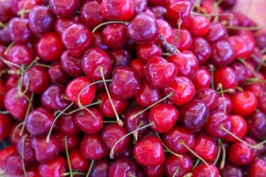 Yeşil saplı bir demet kırmızı kiraz. Kirazlar üst üste yığılmış.