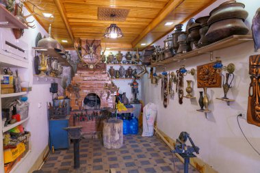 Bir sürü vazo ve duvarında bir saat olan bir oda. Odada büyük bir fırın var.