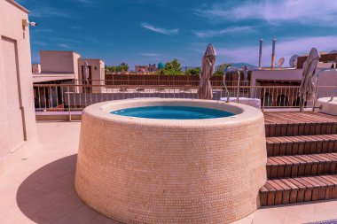 Etrafında taş bir duvar olan küçük bir havuz. Havuz mavi ve beyaz bir kenarı var.