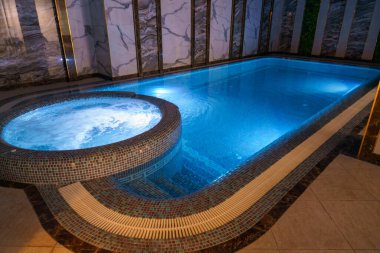 Ortasında küçük bir çeşme olan bir havuz. Havuz mavi ve çeşme beyaz.