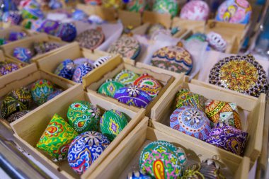 Tahta kutularda renkli boncuklar ve boncuklar sergileniyor. Kutular sıra sıra dizilmiş ve farklı boyutlarda.