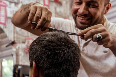 Mutlu berber saçını kesiyor.