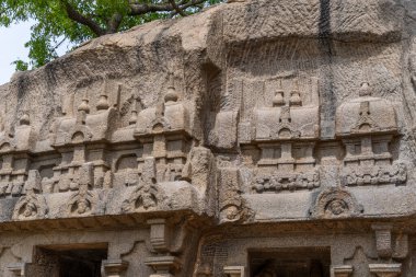Üzerinde oymalar olan büyük bir taş duvar. Oymalar insan ve hayvanlara ait. Duvar çok eski ve çok detay içeriyor.