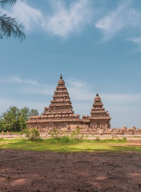 Önünde iki kule ve çimenli bir alan olan büyük bir bina. Çimler yeşil. mahabalipuram