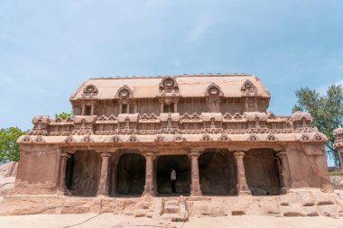 Önünde bir adamın durduğu büyük bir bina. Bina taştan yapılmıştır. mahabalipuram