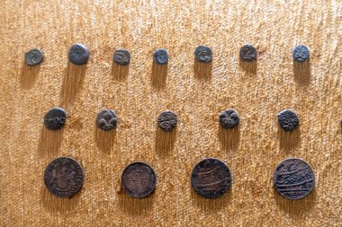 Chennai, Tamil Nadu, Hindistan - 02.07.2025: Eski madeni paraların bir koleksiyonu kahverengi bir kumaş üzerinde sergilenmektedir. Toplamda dokuz sikke var. Chennai 'de.