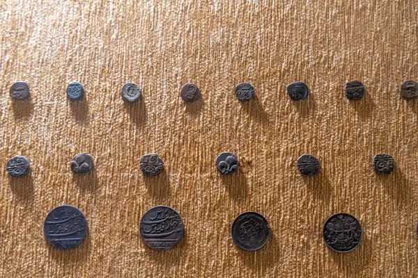 Chennai, Tamil Nadu, Hindistan - 02.07.2025: Kahverengi arka planda bir sıra bozuk para. Bozukluklar farklı boyutlarda ve şekillerde. Chennai 'de.