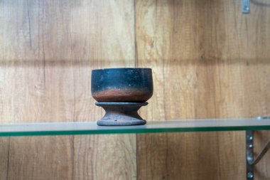 Chennai, Tamil Nadu, Hindistan - 02.07.2025: Siyah ve kahverengi bir seramik kase bir rafta duruyor. Raflar ahşaptan yapılmıştır. Chennai 'de.