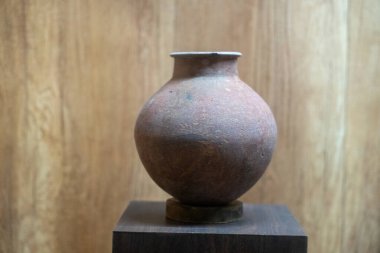 Chennai, Tamil Nadu, Hindistan - 02.07.2025: Ahşap bir kaideye kahverengi bir seramik vazo yerleştirilmiştir. Heykel ahşaptan yapılmıştır. Chennai 'de.