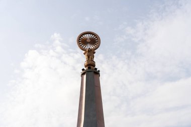 Chennai, Tamil Nadu, Hindistan - 02.07.2025: Üzerinde altın tekerlek olan uzun, beyaz bir sütun. Tekerlek bir daire ile çevrilidir. Chennai 'de.
