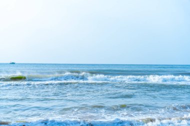 Chennai, Tamil Nadu, Hindistan - 02.07.2025: Okyanus mavi ve dalgalar çarpışıyor. Suda bir tekne var. Gökyüzü açık. Chennai 'de.